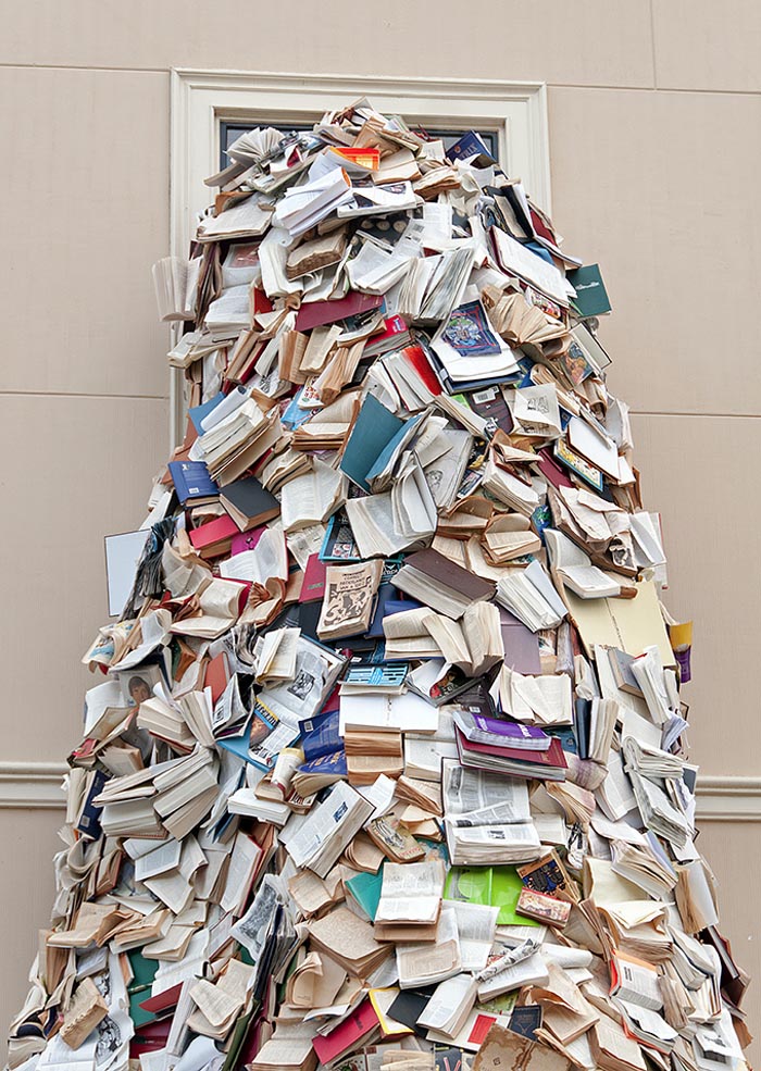Book sculpture of thousands of books pouring out Museum Meermanno window, by Alicia Martin, contemporary sculpture from Spain